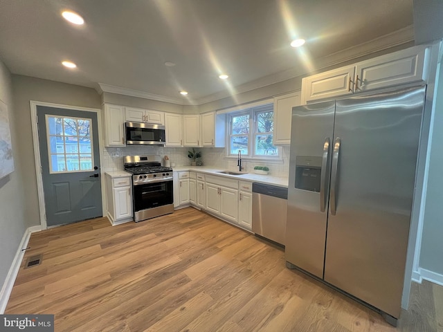 kitchen featuring white cabinets, stainless steel appliances, a healthy amount of sunlight, and light hardwood / wood-style floors