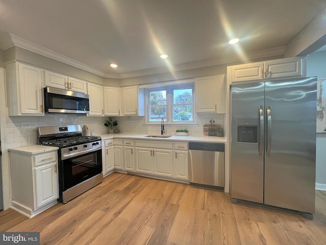 kitchen with decorative backsplash, light wood-type flooring, stainless steel appliances, sink, and white cabinetry