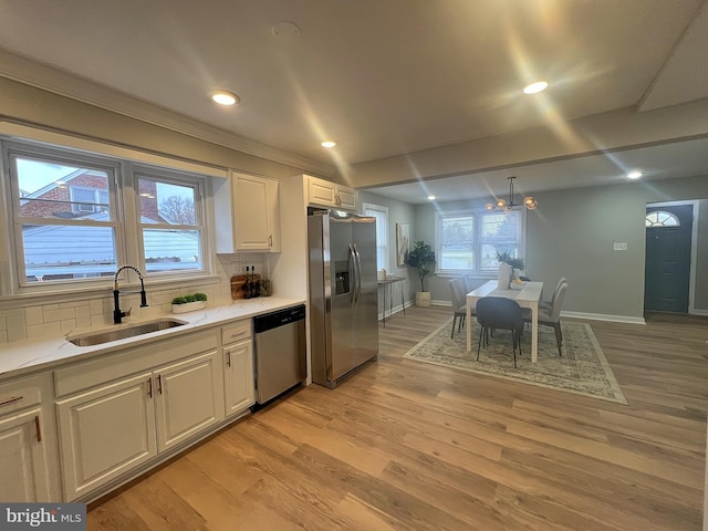 kitchen featuring decorative backsplash, sink, stainless steel appliances, and light hardwood / wood-style flooring