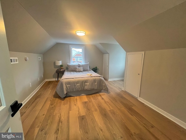 bedroom with lofted ceiling and light wood-type flooring