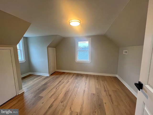 additional living space with light hardwood / wood-style flooring and vaulted ceiling