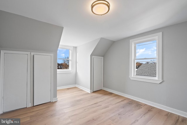 additional living space with lofted ceiling, light hardwood / wood-style floors, and a healthy amount of sunlight