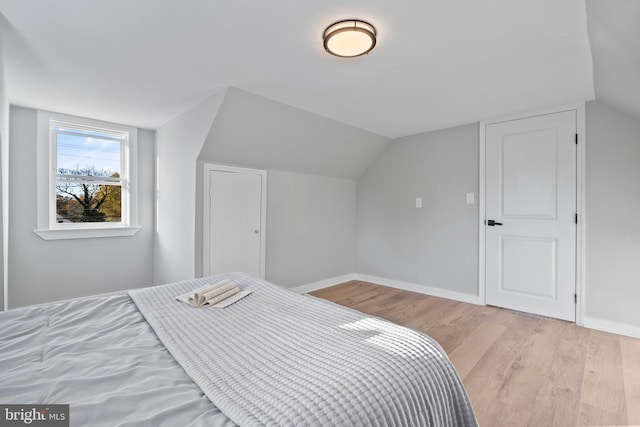 bedroom featuring lofted ceiling and light hardwood / wood-style flooring