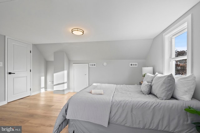 bedroom with light hardwood / wood-style floors and vaulted ceiling