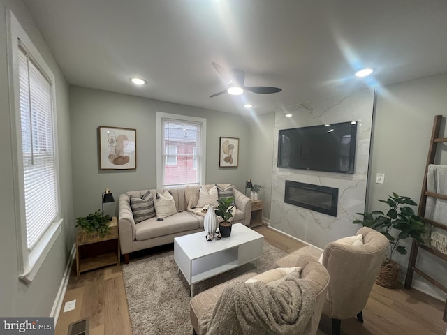 living room with hardwood / wood-style floors, ceiling fan, and a premium fireplace