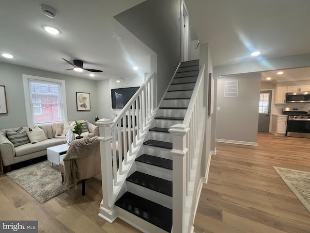 staircase with ceiling fan and hardwood / wood-style flooring