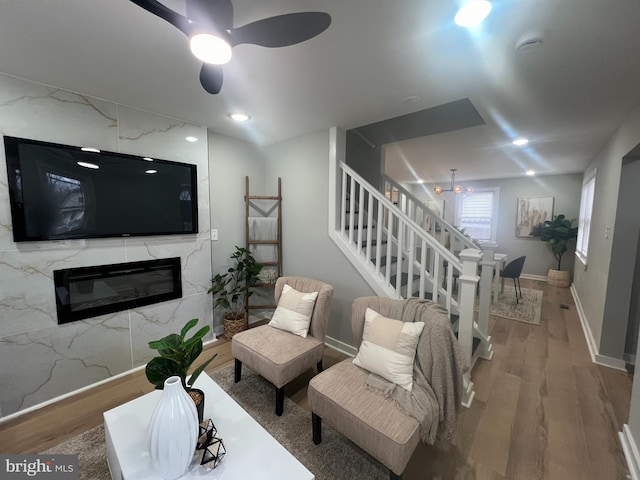 living room with hardwood / wood-style floors, ceiling fan, and a premium fireplace