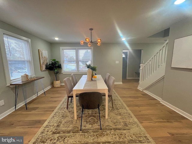 dining space with a wealth of natural light, a notable chandelier, and light wood-type flooring