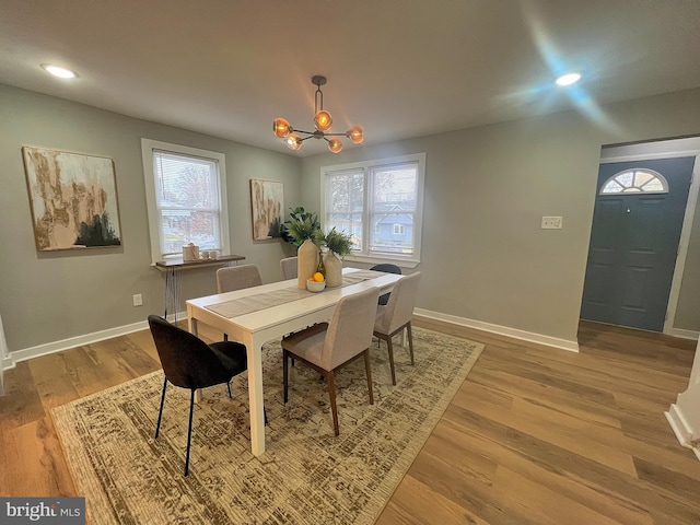 dining space with a chandelier, a wealth of natural light, and light hardwood / wood-style flooring