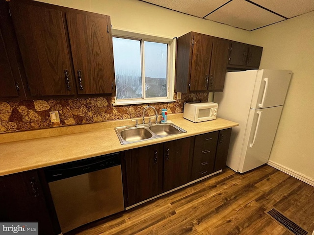 kitchen featuring backsplash, dark hardwood / wood-style flooring, white appliances, and sink