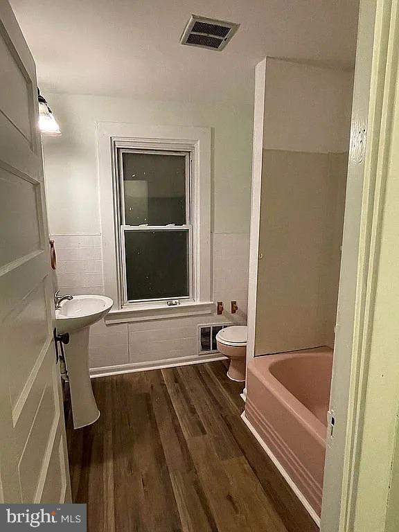 bathroom featuring hardwood / wood-style flooring, toilet, and independent shower and bath