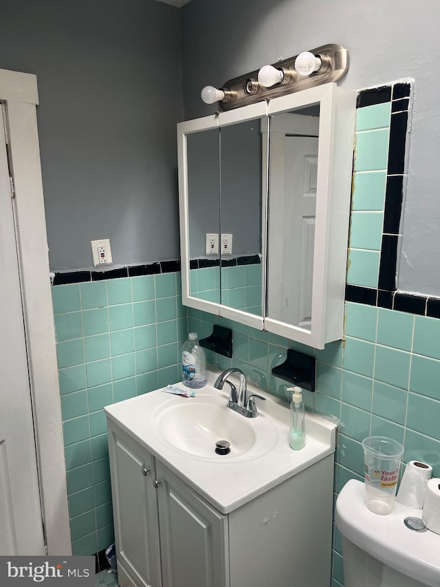 bathroom featuring vanity, tile walls, and toilet