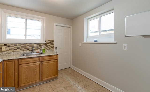 kitchen featuring decorative backsplash, light stone countertops, sink, and light tile patterned floors