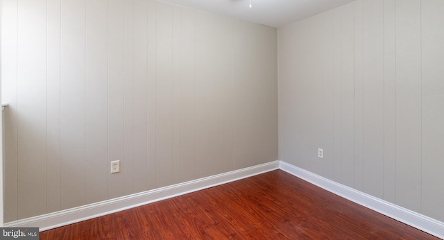 unfurnished room with hardwood / wood-style flooring and wooden walls