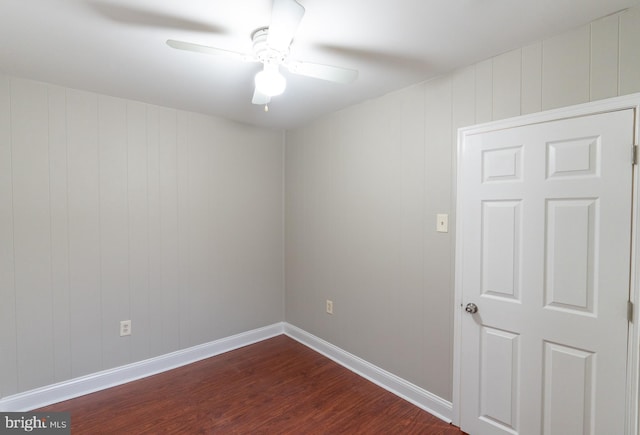 spare room featuring ceiling fan, wood walls, and dark hardwood / wood-style floors