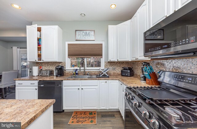 kitchen with dark hardwood / wood-style flooring, white cabinetry, sink, and appliances with stainless steel finishes