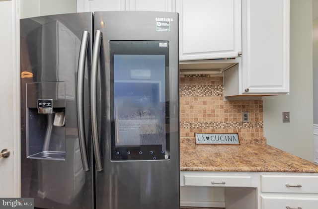 kitchen with white cabinets, stainless steel fridge, backsplash, and light stone counters