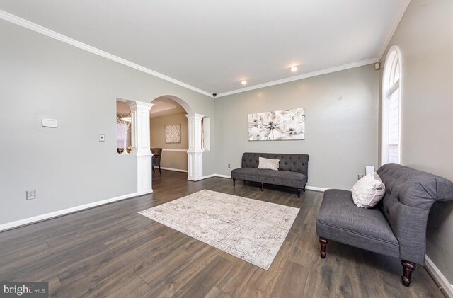 living room featuring decorative columns, crown molding, and dark wood-type flooring