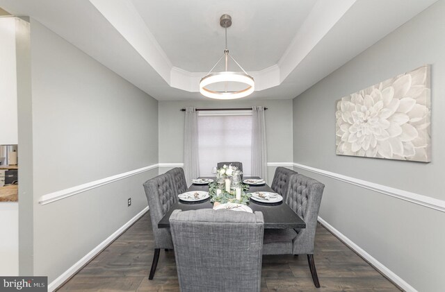 dining space with dark hardwood / wood-style floors and a tray ceiling