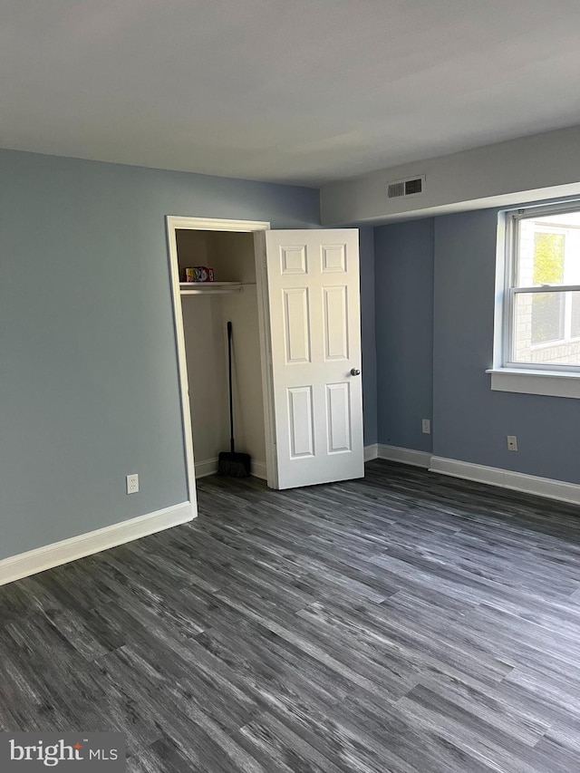 unfurnished bedroom with a closet and dark wood-type flooring