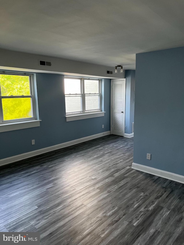 empty room featuring a healthy amount of sunlight and dark hardwood / wood-style floors