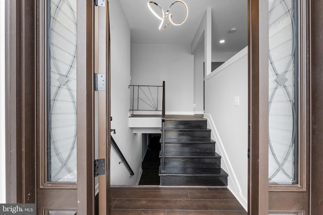 stairs with wood-type flooring and a notable chandelier