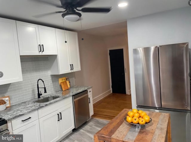 kitchen featuring white cabinets, light stone countertops, sink, and appliances with stainless steel finishes