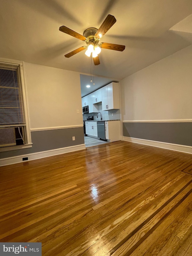 unfurnished living room featuring hardwood / wood-style floors, ceiling fan, and sink