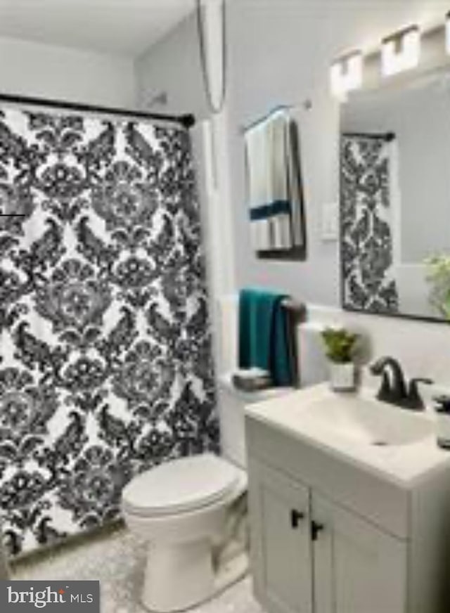 bathroom featuring a shower with shower curtain, vanity, and toilet