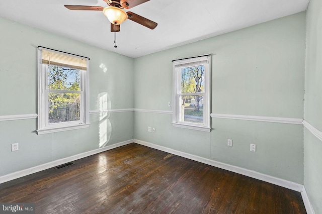 empty room with dark hardwood / wood-style flooring, ceiling fan, and plenty of natural light