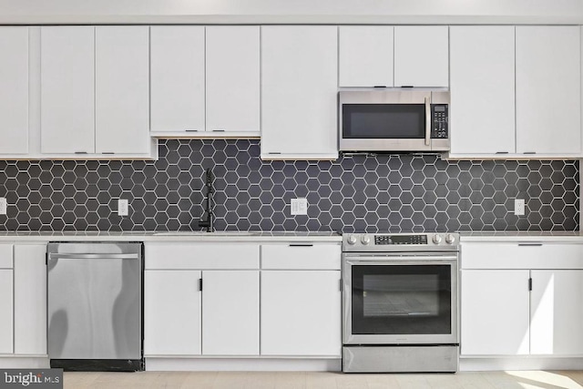 kitchen with appliances with stainless steel finishes, backsplash, white cabinetry, and sink