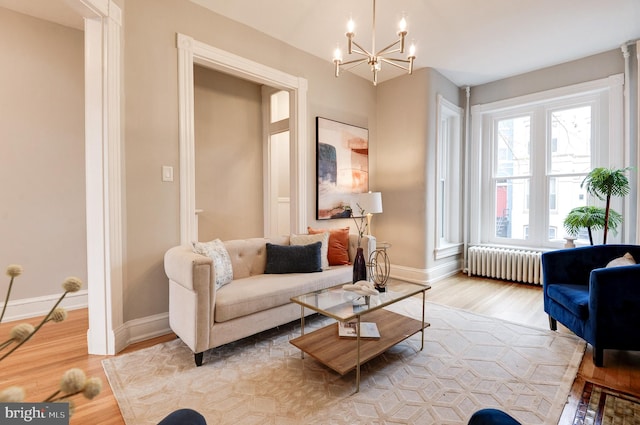 living room featuring radiator heating unit, a chandelier, and light hardwood / wood-style flooring