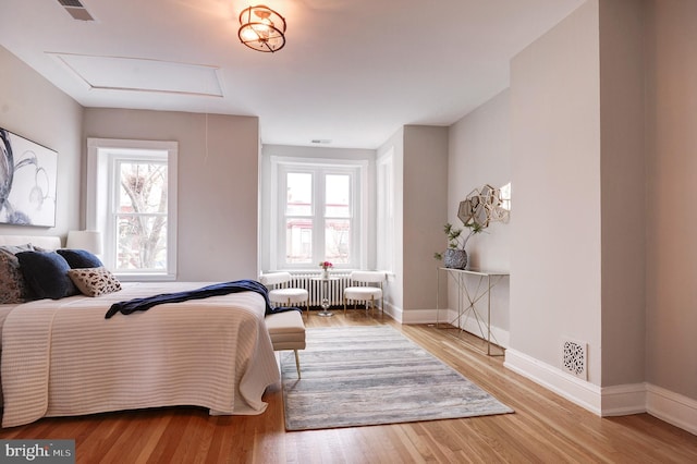 bedroom with radiator and light hardwood / wood-style flooring