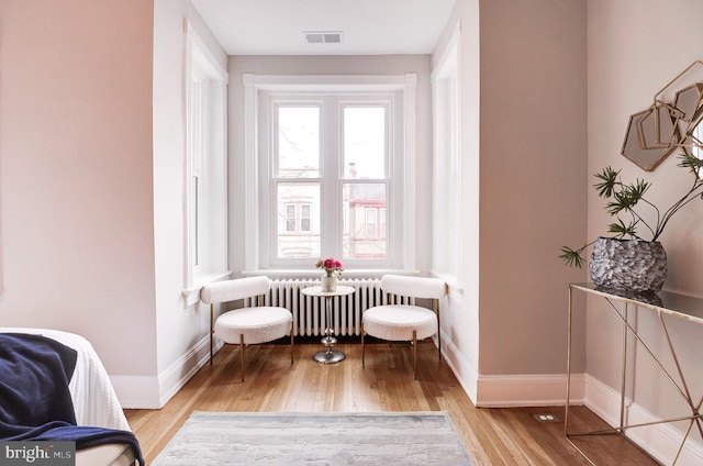 living area featuring light wood-type flooring and radiator heating unit