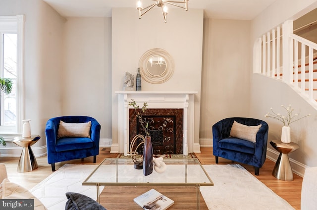 living room featuring hardwood / wood-style flooring, a premium fireplace, and an inviting chandelier