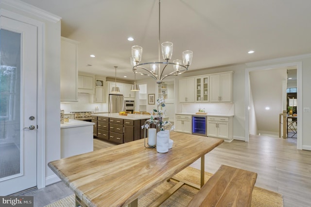 kitchen featuring stainless steel appliances, a kitchen island, white cabinets, wine cooler, and hanging light fixtures