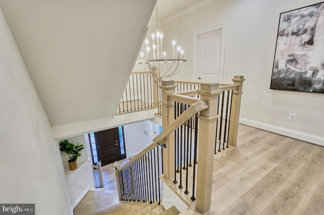 stairs with hardwood / wood-style flooring, crown molding, and a chandelier