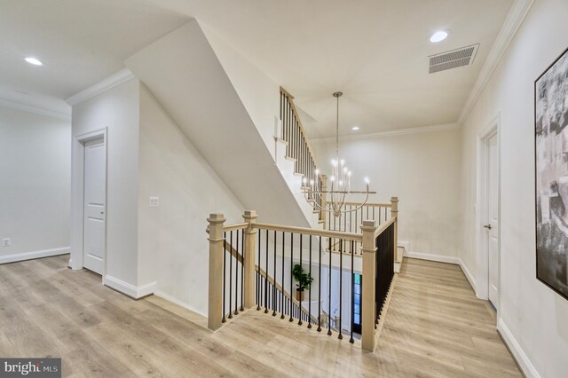 stairway with hardwood / wood-style floors, ornamental molding, and a chandelier