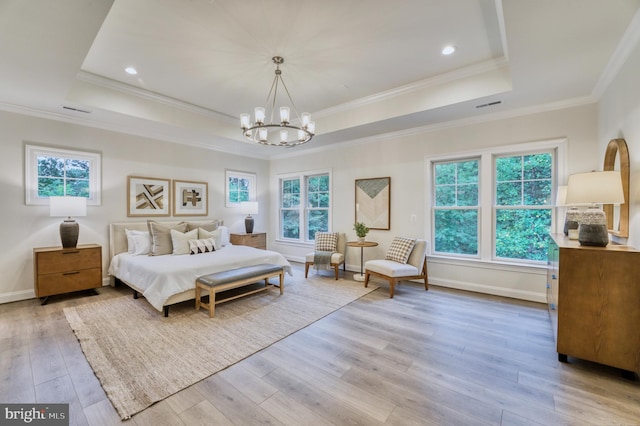 bedroom with a notable chandelier, light wood-type flooring, ornamental molding, and a tray ceiling