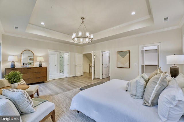 bedroom featuring a raised ceiling, light wood-type flooring, ornamental molding, and a chandelier