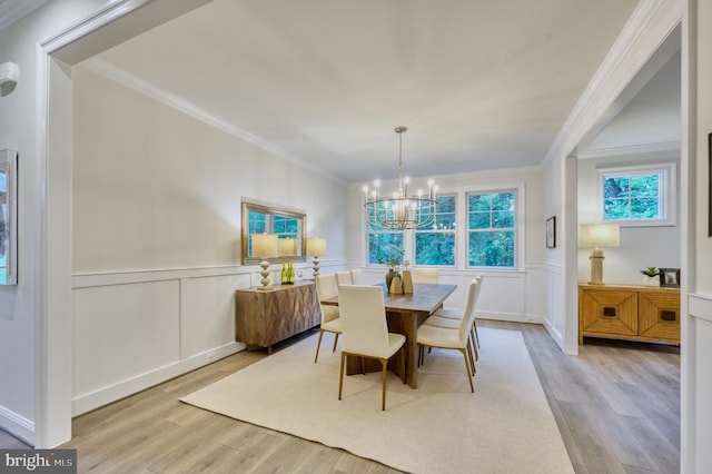 dining room featuring crown molding, light hardwood / wood-style flooring, and an inviting chandelier