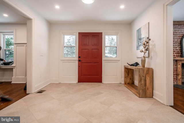 entrance foyer with a brick fireplace and a healthy amount of sunlight