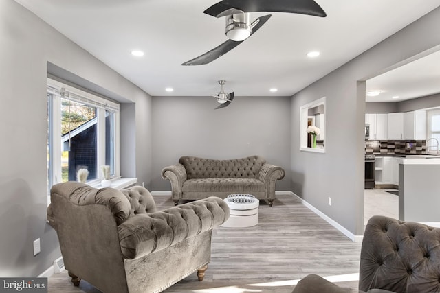 living room with ceiling fan, light hardwood / wood-style floors, and sink