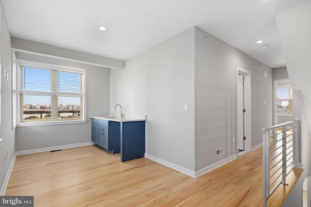 interior space with sink, light hardwood / wood-style floors, and blue cabinets