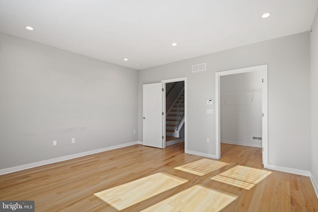 unfurnished bedroom with a closet, a spacious closet, and light hardwood / wood-style flooring