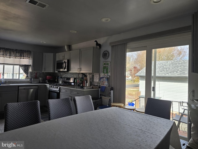 kitchen with gray cabinetry, decorative backsplash, sink, and appliances with stainless steel finishes