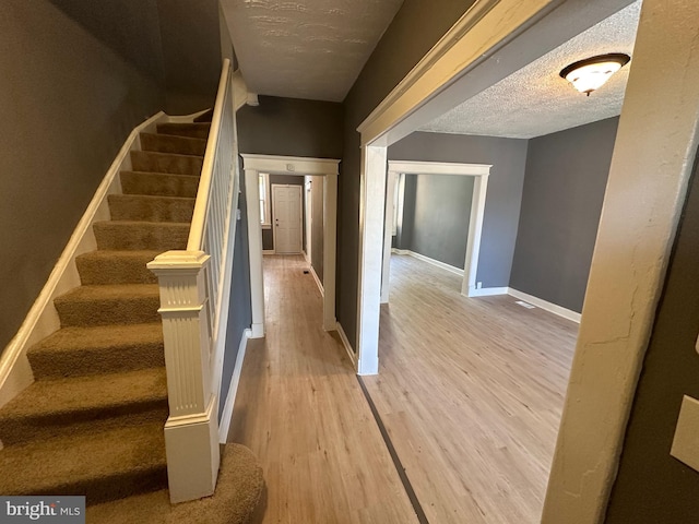 staircase featuring a textured ceiling and hardwood / wood-style flooring