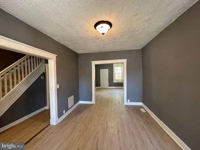 empty room with a textured ceiling and light wood-type flooring