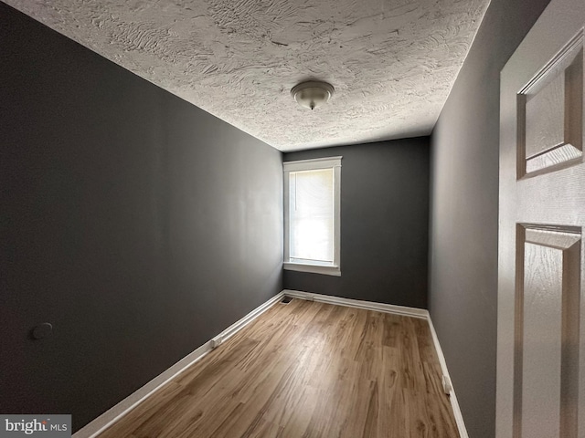 unfurnished room with a textured ceiling and hardwood / wood-style flooring