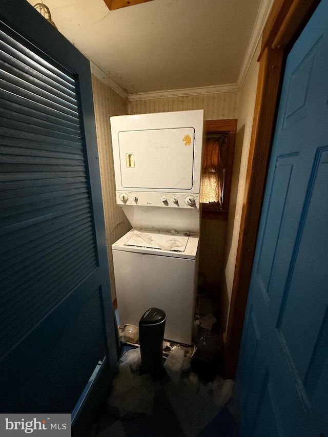 laundry area with wood walls, crown molding, and stacked washer / dryer